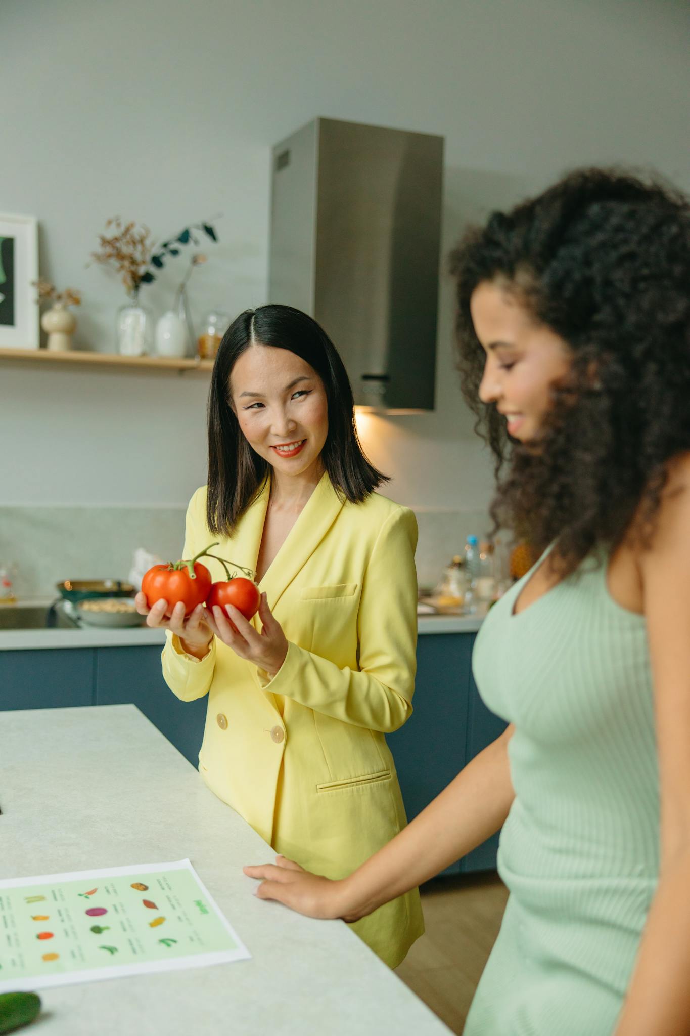Nutritionist and client discussing healthy food options with fresh tomatoes in a modern kitchen.